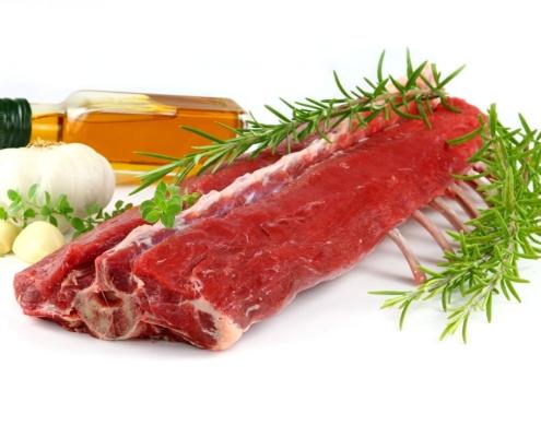 trimmed rack of raw lamb with oregano, garlic, rosemary and vinegar