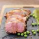 A cannon of lamb on a slate with peas.